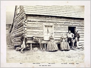 family standing next to log cabin